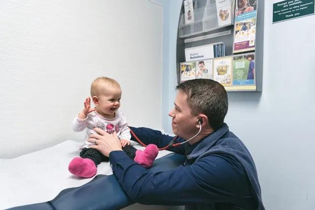 a baby highfiving their pediatrician